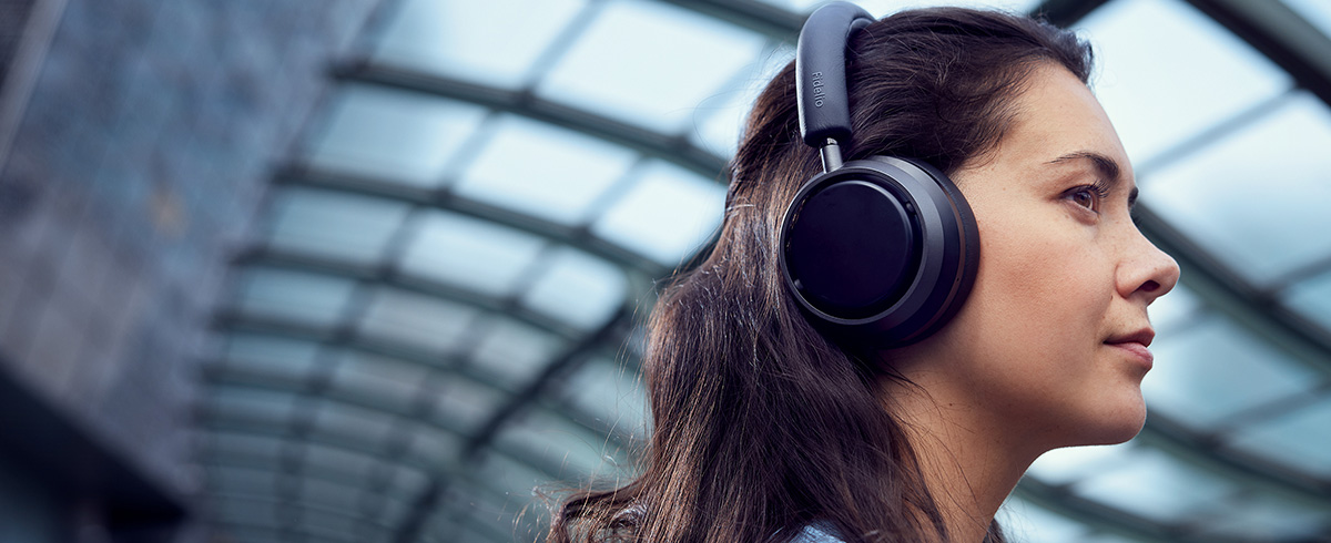 Mujer disfrutando de la m&uacute;sica mientras viaja con auriculares Philips L4